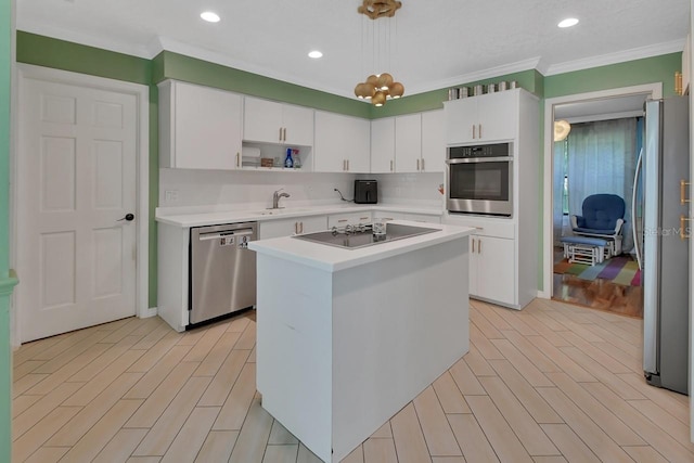 kitchen with white cabinets, appliances with stainless steel finishes, a center island, light countertops, and pendant lighting