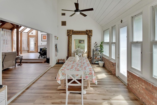 dining space with light wood finished floors, brick wall, and visible vents