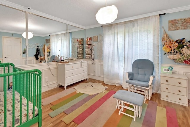 bedroom featuring light wood-style floors, ornamental molding, and wainscoting