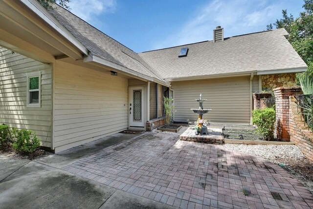 rear view of property with a chimney, roof with shingles, and a patio area