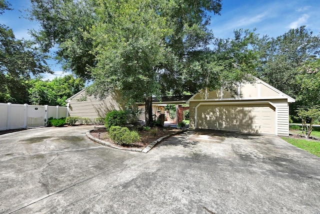 view of front of home featuring driveway, a garage, and fence