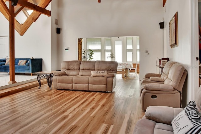 living area with light wood-style floors, high vaulted ceiling, and beam ceiling