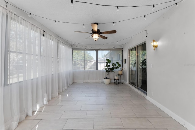 unfurnished sunroom featuring a ceiling fan