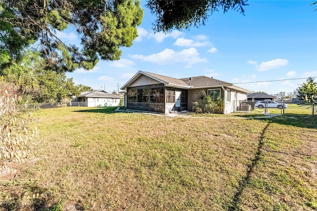 rear view of house with a gate, a sunroom, a yard, and fence