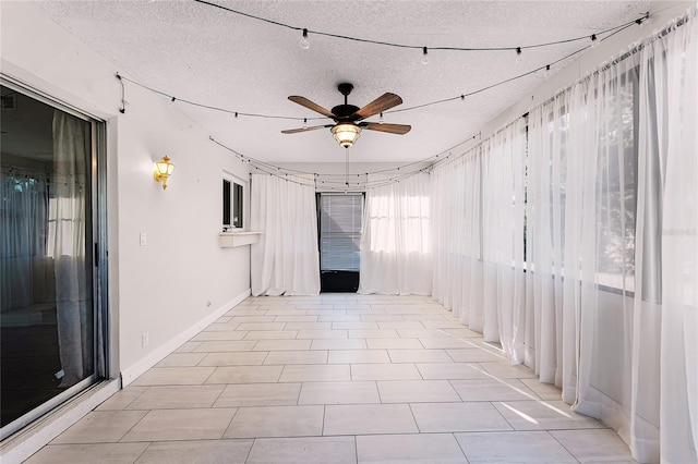 spare room featuring ceiling fan, light tile patterned floors, a textured ceiling, and baseboards