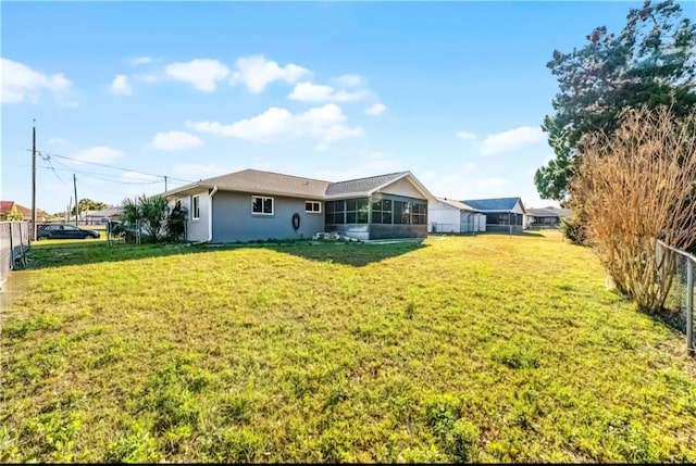 rear view of property with a lawn, fence, and a sunroom