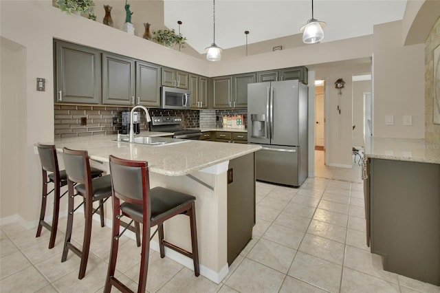 kitchen with light tile patterned floors, tasteful backsplash, appliances with stainless steel finishes, a sink, and a peninsula