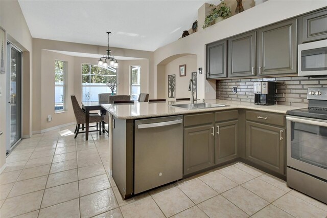 kitchen with light tile patterned floors, stainless steel appliances, tasteful backsplash, light countertops, and a sink