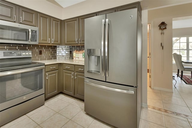 kitchen featuring light tile patterned floors, appliances with stainless steel finishes, backsplash, and baseboards