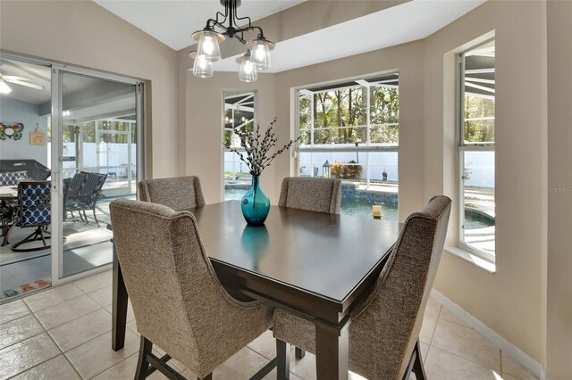 dining room with lofted ceiling, light tile patterned floors, a chandelier, and baseboards