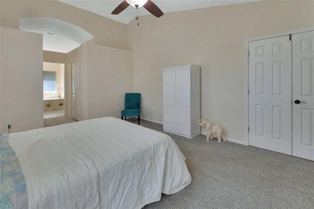 carpeted bedroom with arched walkways, visible vents, ceiling fan, ensuite bath, and baseboards