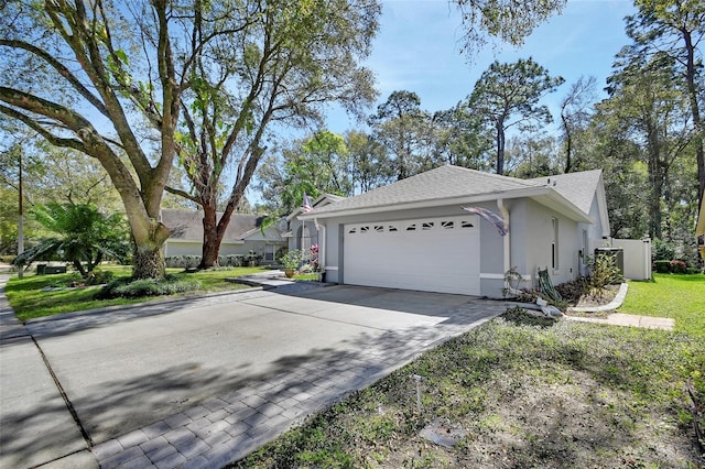 view of home's exterior with a garage, a shingled roof, decorative driveway, and stucco siding