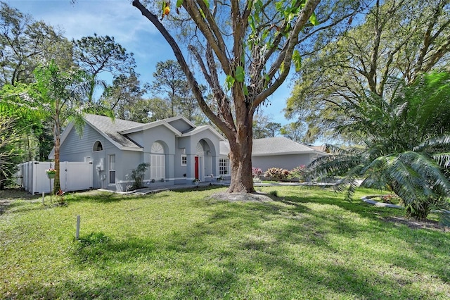 view of front of home with a gate, fence, a front lawn, and stucco siding