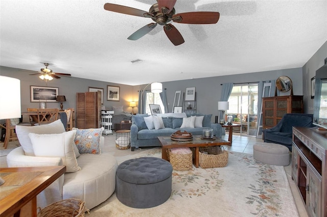 living area featuring light tile patterned floors, a textured ceiling, and visible vents