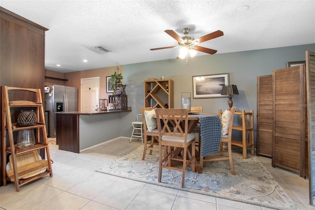 dining room featuring light tile patterned floors, visible vents, ceiling fan, a textured ceiling, and baseboards