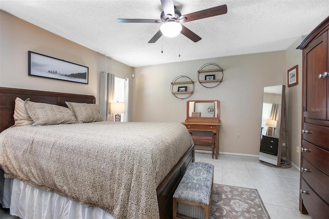 bedroom with light tile patterned floors, a ceiling fan, baseboards, and a textured ceiling