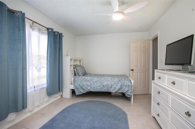 bedroom with ceiling fan, a textured ceiling, and light tile patterned floors