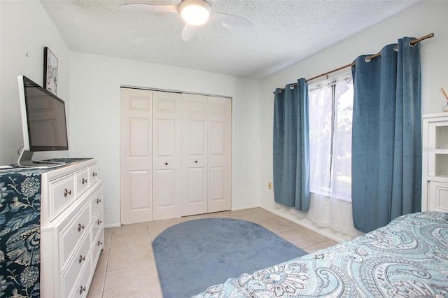 bedroom with a ceiling fan, a closet, a textured ceiling, and light tile patterned floors