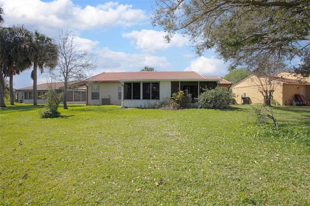 rear view of property with a tile roof, a lawn, and stucco siding