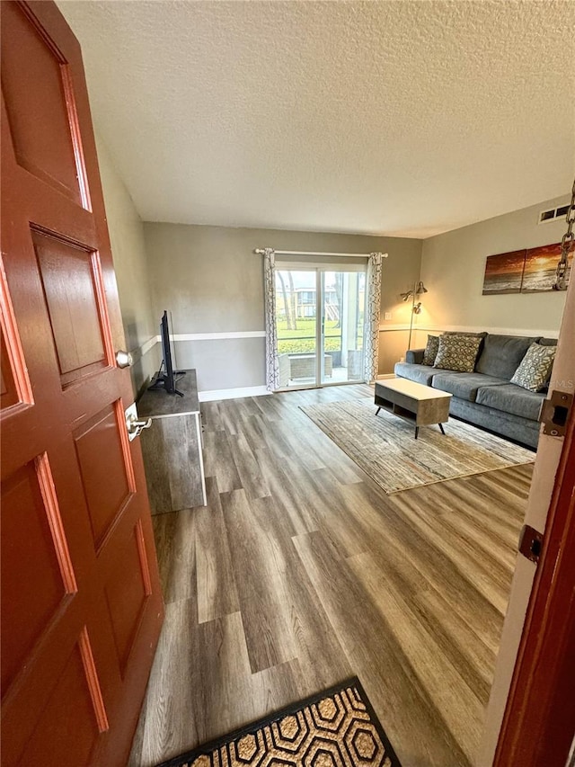 living room with visible vents, a textured ceiling, and wood finished floors