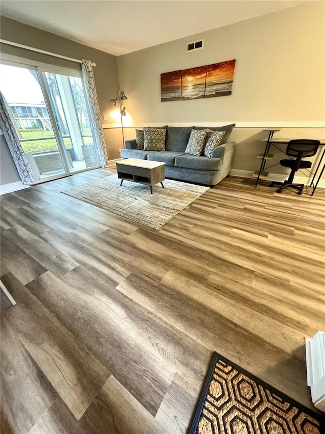 living room featuring wood finished floors, visible vents, and baseboards