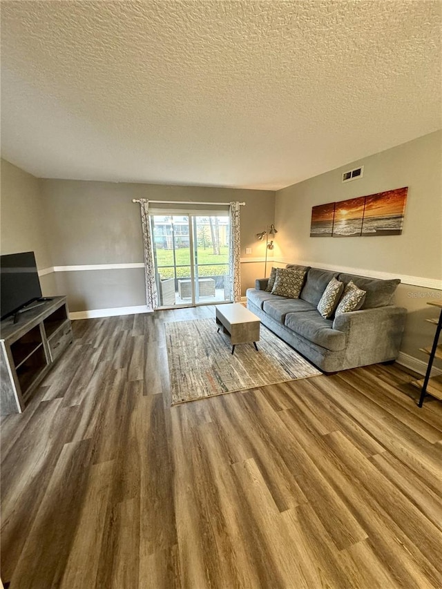 living room with a textured ceiling, wood finished floors, and visible vents