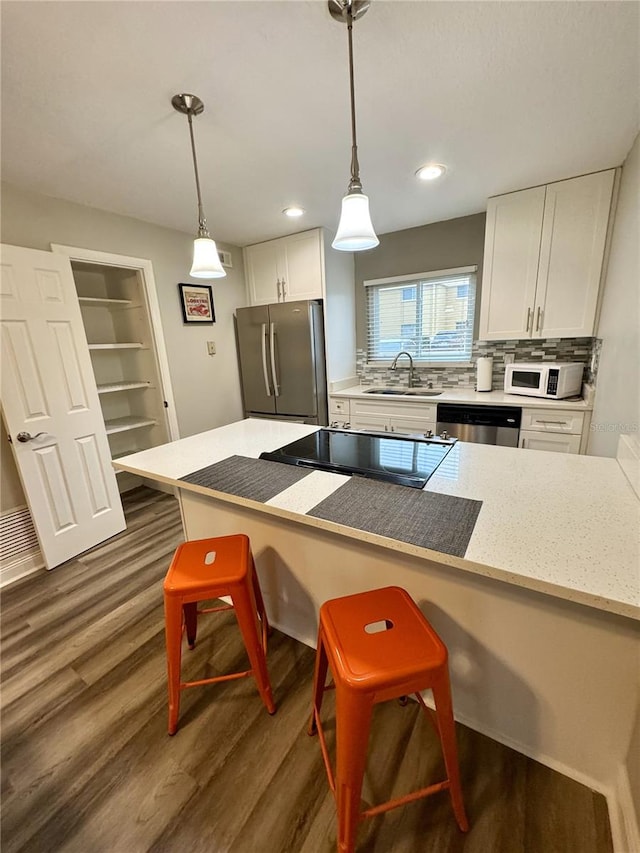 kitchen with white cabinets, a kitchen breakfast bar, decorative light fixtures, stainless steel appliances, and a sink