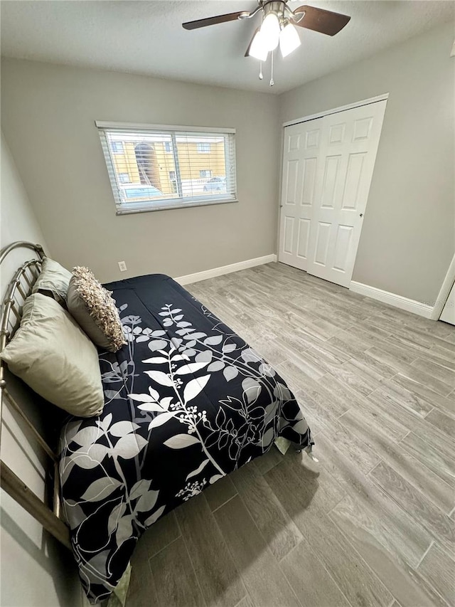 bedroom featuring ceiling fan, a closet, baseboards, and wood finished floors