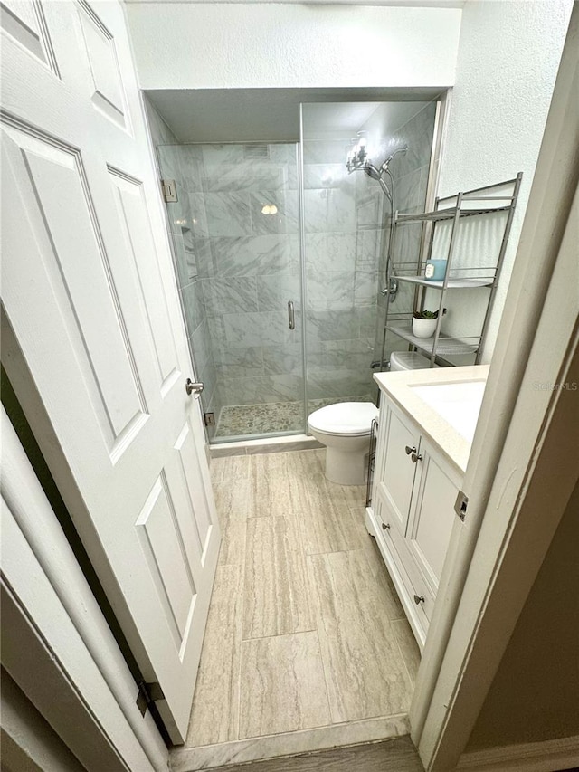 bathroom with toilet, wood finished floors, a shower stall, and vanity