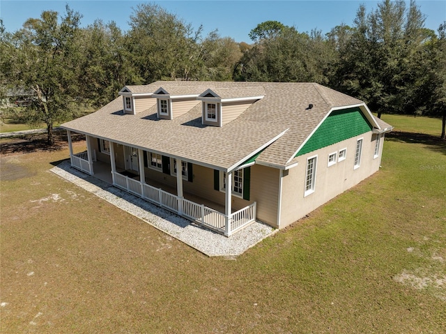 exterior space with a shingled roof, covered porch, and a lawn