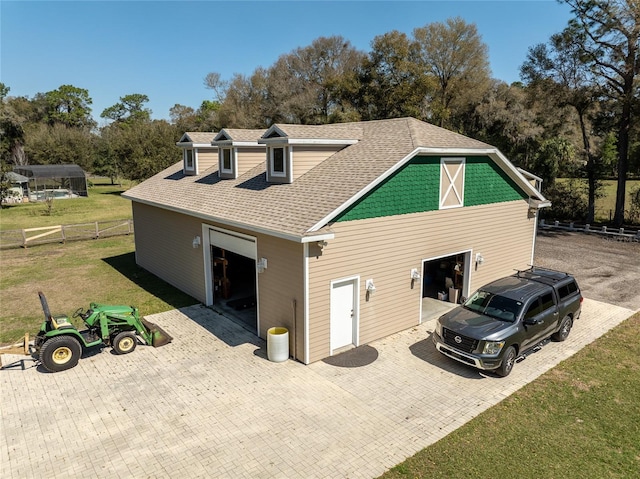 view of side of property with a garage, driveway, a lawn, roof with shingles, and fence