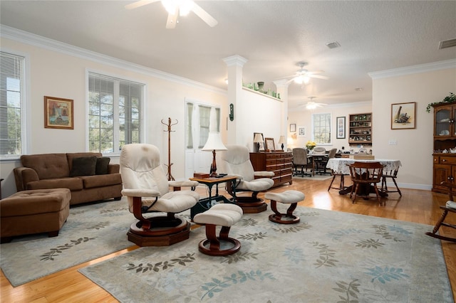 living area featuring crown molding, visible vents, ceiling fan, and wood finished floors