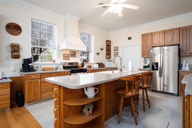 kitchen featuring brown cabinetry, stainless steel appliances, light countertops, open shelves, and a sink