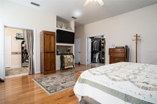 bedroom featuring a closet, visible vents, a textured ceiling, and wood finished floors