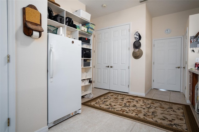 kitchen with tile patterned flooring, freestanding refrigerator, and baseboards