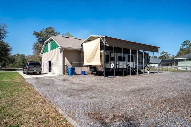 exterior space with roof with shingles, gravel driveway, and fence