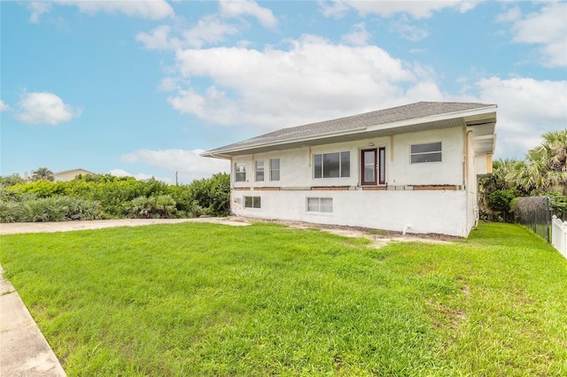 back of property with stucco siding, a lawn, and fence