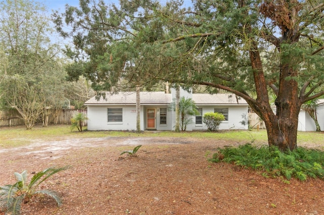 ranch-style house with dirt driveway and fence