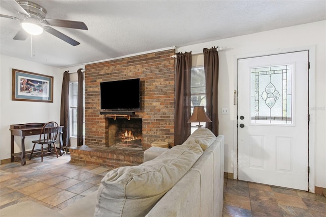 living room with plenty of natural light, a fireplace, a ceiling fan, and stone finish flooring