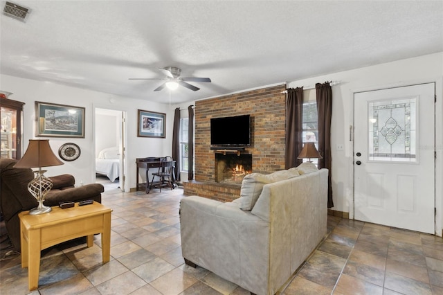 living area featuring a brick fireplace, plenty of natural light, visible vents, and a textured ceiling