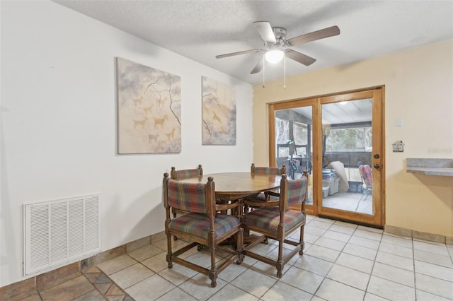 dining area with a ceiling fan, visible vents, a textured ceiling, and light tile patterned floors