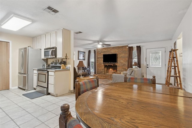 dining space featuring light tile patterned floors, a fireplace, visible vents, and a healthy amount of sunlight