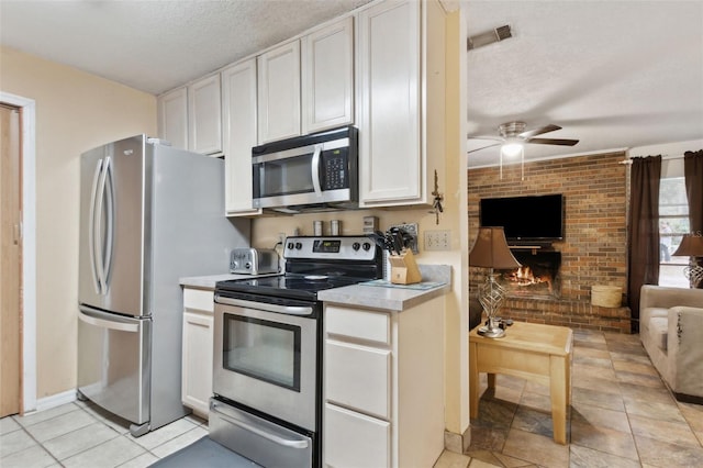 kitchen featuring a textured ceiling, white cabinetry, open floor plan, light countertops, and appliances with stainless steel finishes