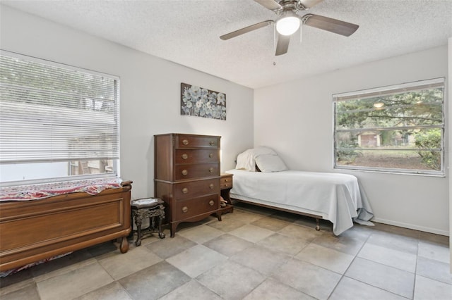 bedroom featuring a textured ceiling, a ceiling fan, and baseboards