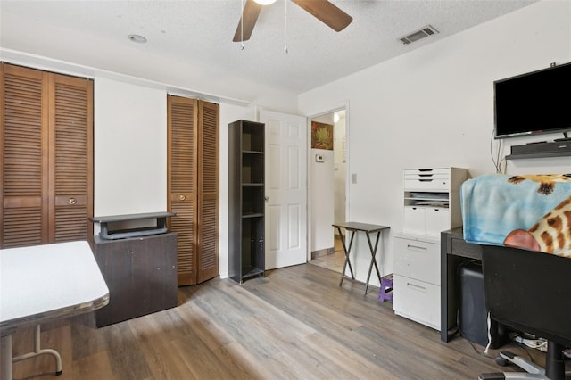 office space with a ceiling fan, a textured ceiling, visible vents, and wood finished floors