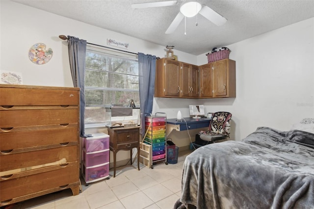 bedroom with a textured ceiling, built in desk, light tile patterned flooring, and a ceiling fan