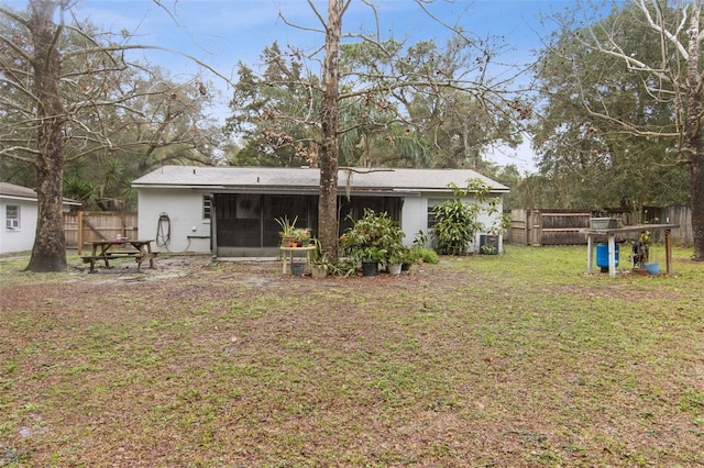 rear view of house featuring a sunroom, a lawn, an attached garage, and fence