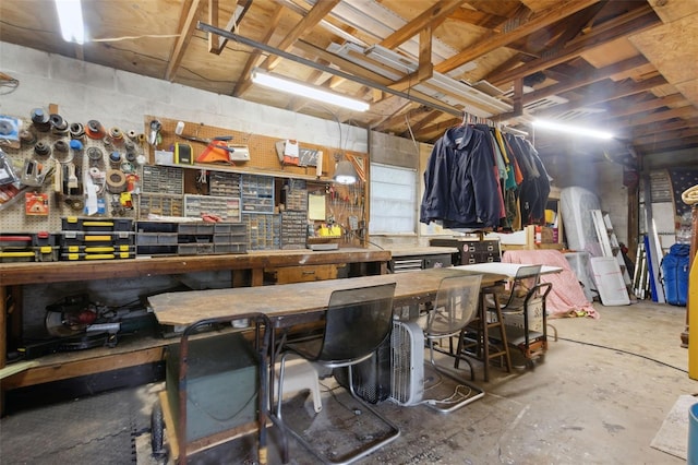 interior space with concrete block wall, unfinished concrete floors, and a workshop area