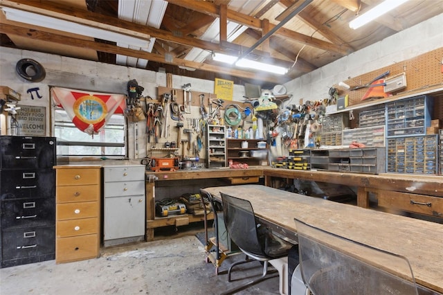 misc room with unfinished concrete floors, lofted ceiling, and a workshop area