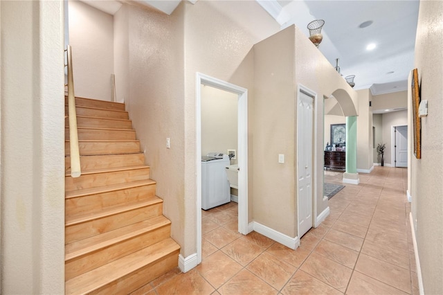 staircase featuring arched walkways, baseboards, washer / dryer, and tile patterned floors